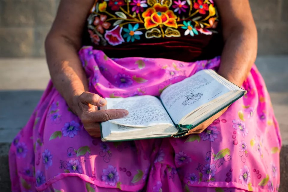 Zapotec woman in traditional dress with open Bible