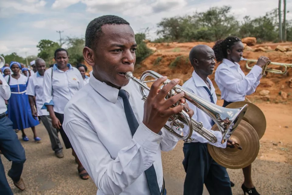Tharaka man blowing trumpet in a parade in Kenya