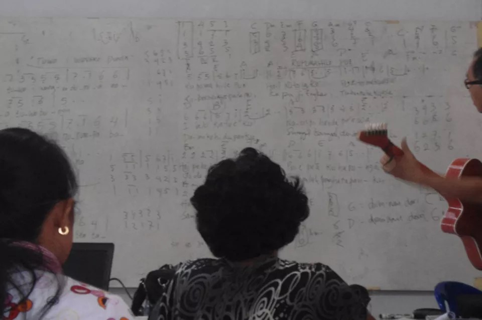 Southeast Asian women write songs in their language on a whiteboard