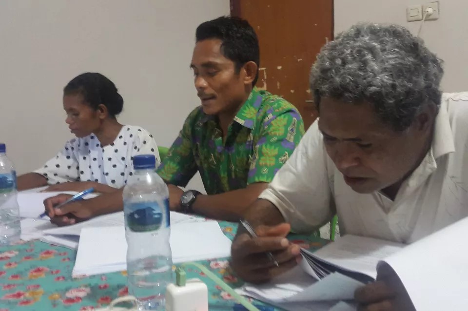 Bible translators in the Pacific region sit at a table drafting and editing manuscripts.