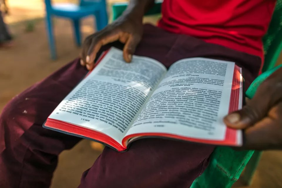 African man sitting with open Bible on lap