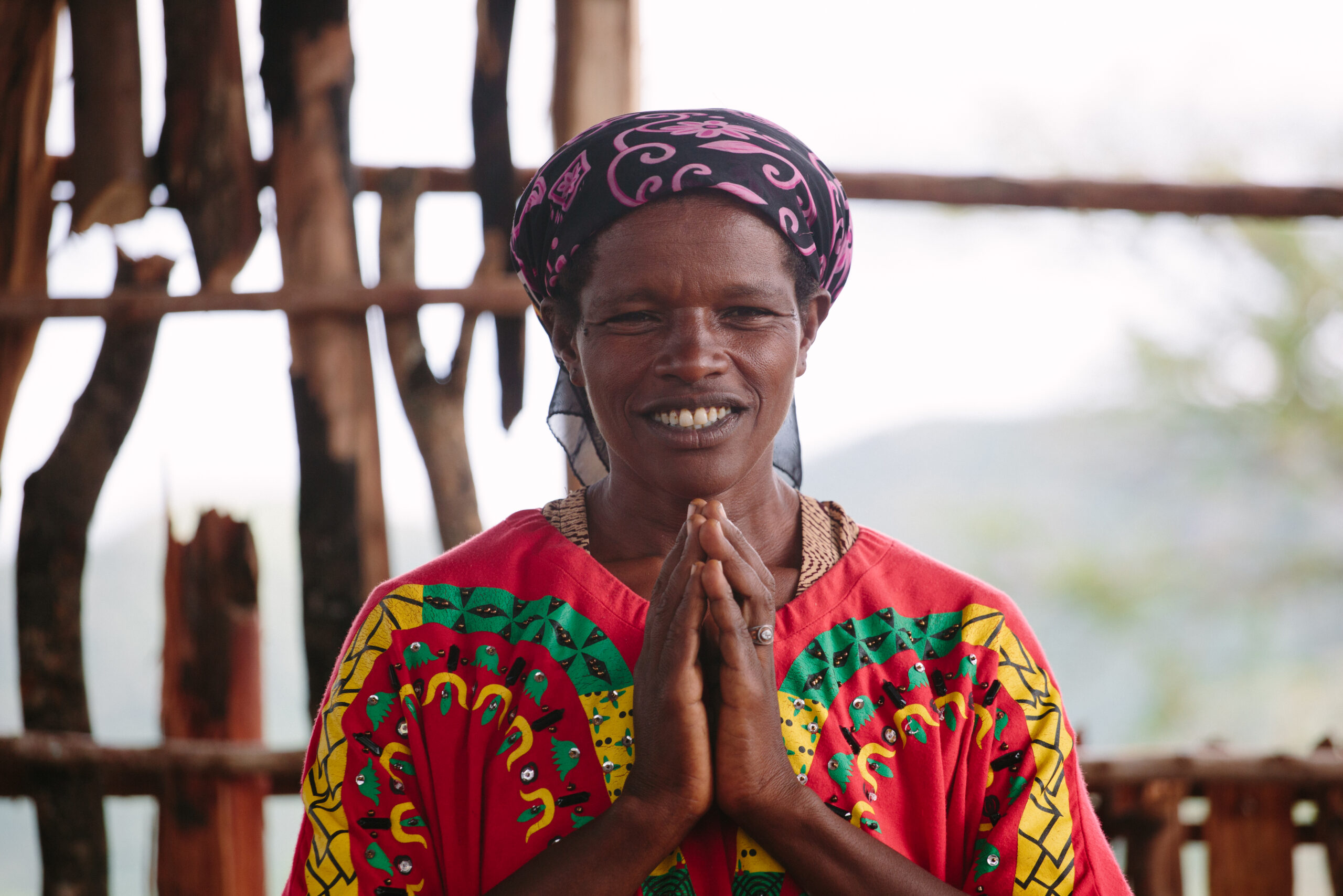 Ethiopian woman in traditional dress lifts hands in prayer