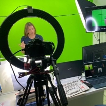 A Deaf translation team member signs in front of a green screen to make a video for the LIBRAS project in Brazil.