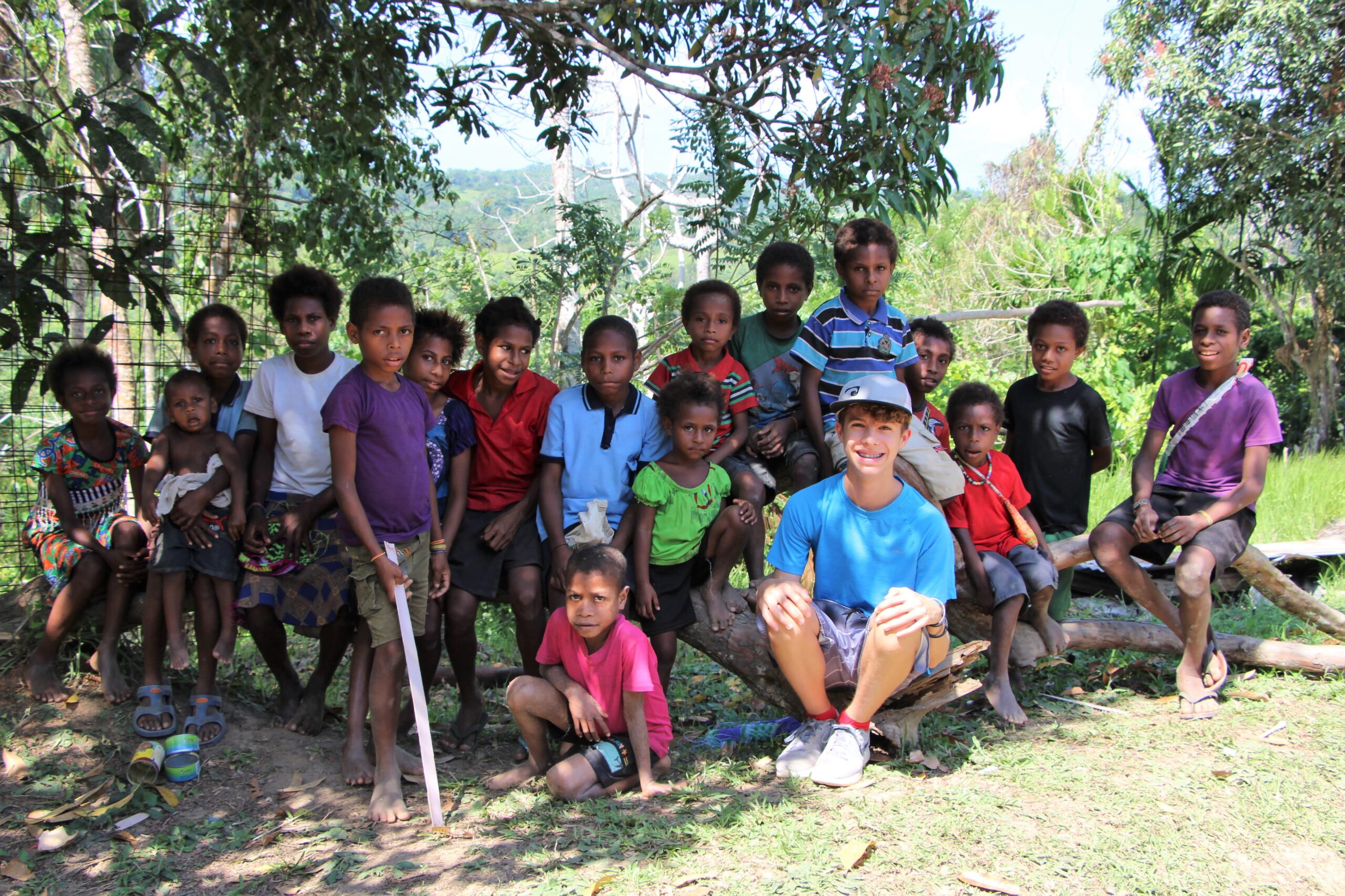 American teenage boy with group of local children in Papua New Guinea