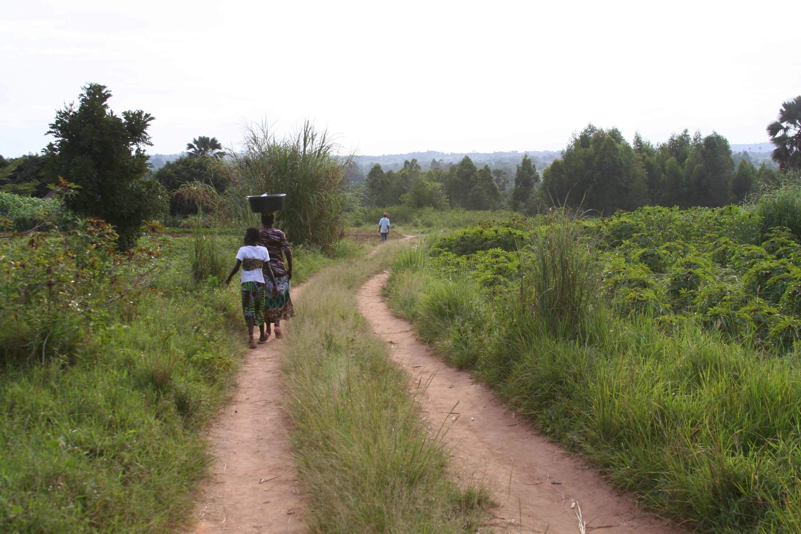 People walk along a dirt road in the Ndrulo area of Uganda