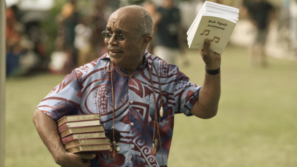 Man happily holding up stacks of Bibles and song books