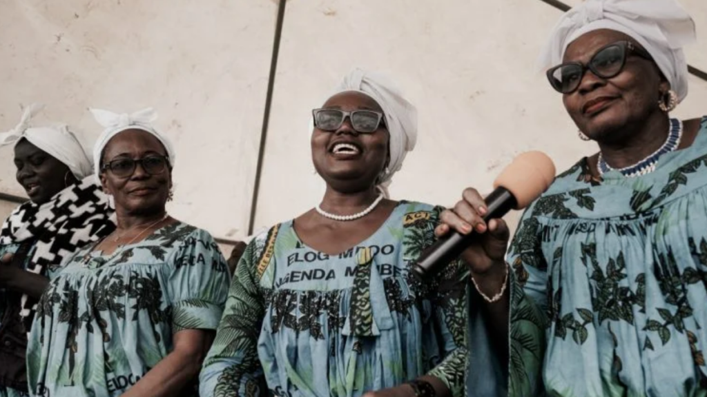 three women smiling and singing with a microphone