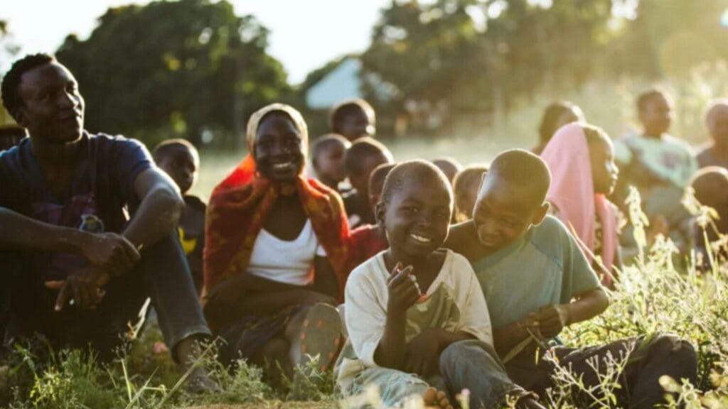 a group sitting in a field celebrating a Bible translation in their own language