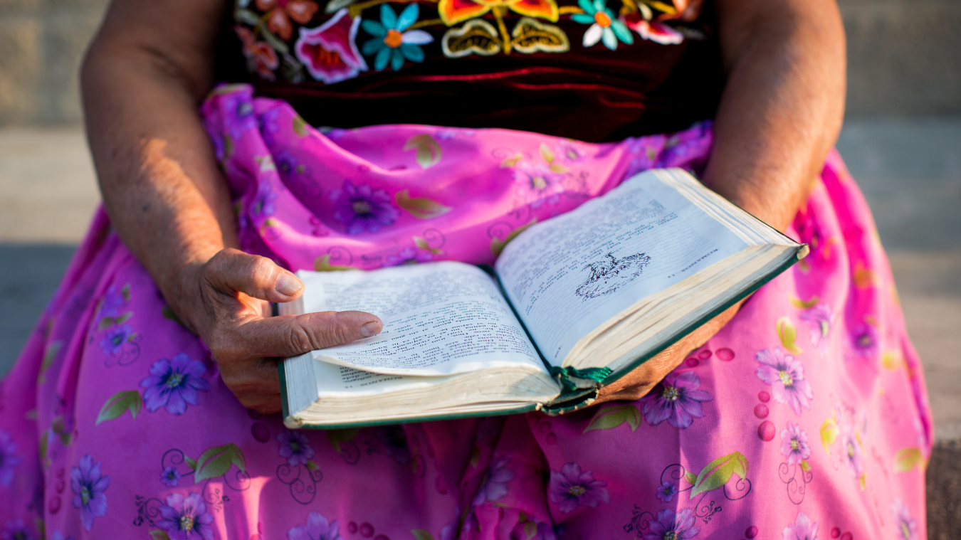 woman in bright pink skirt holding a bible open in her lap